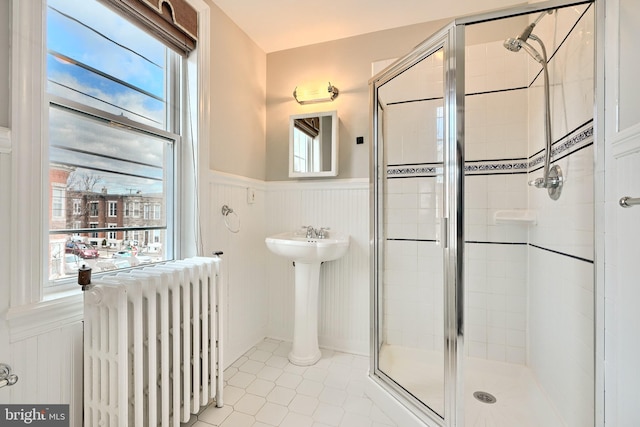 bathroom with tile patterned flooring, radiator heating unit, and walk in shower