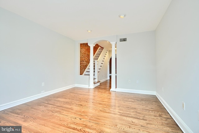 spare room with decorative columns and light hardwood / wood-style flooring