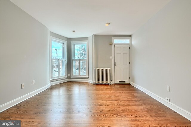 foyer entrance featuring radiator heating unit, hardwood / wood-style flooring, and a healthy amount of sunlight