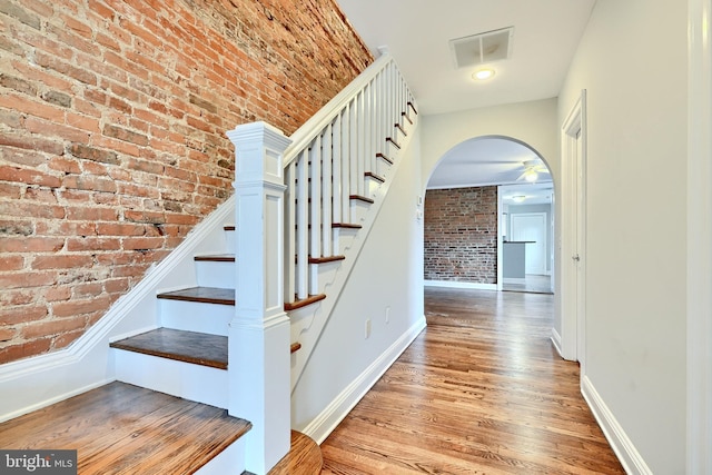 stairway featuring hardwood / wood-style flooring and brick wall