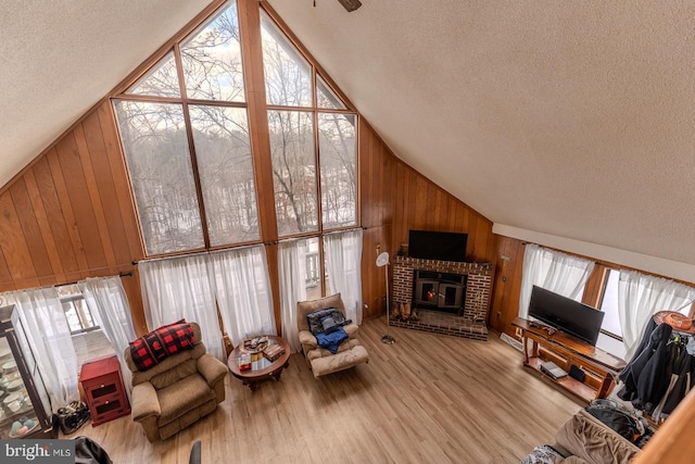 living room featuring a textured ceiling, wood walls, light wood-type flooring, and vaulted ceiling