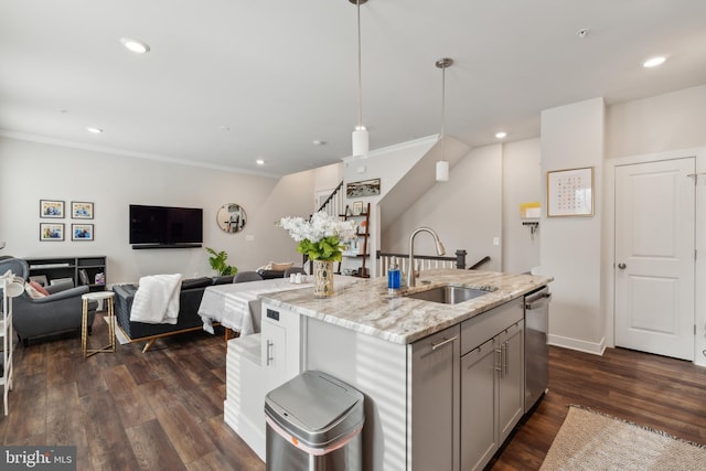 kitchen with dishwasher, an island with sink, sink, hanging light fixtures, and light stone counters