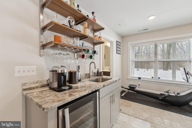 kitchen featuring wine cooler, sink, white cabinetry, light tile patterned floors, and light stone countertops