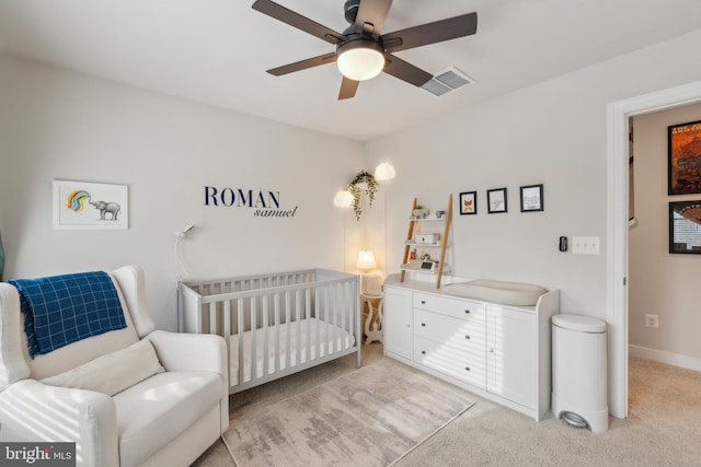 bedroom with ceiling fan, a nursery area, and light carpet