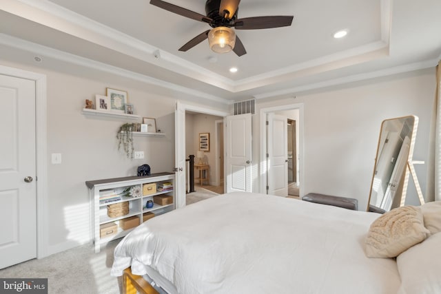 bedroom with ornamental molding, ceiling fan, light colored carpet, and a tray ceiling