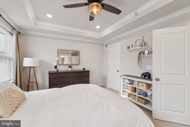 bedroom with light carpet, ceiling fan, and a raised ceiling