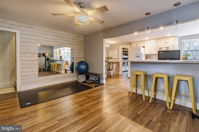 exercise area featuring ceiling fan, rustic walls, and light hardwood / wood-style flooring