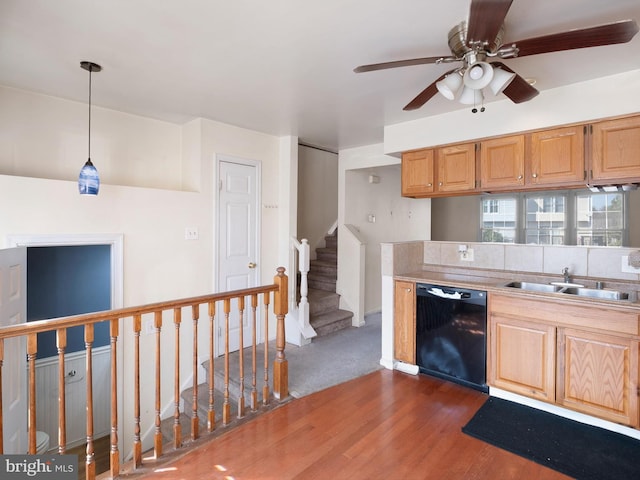 kitchen featuring a sink, ceiling fan, black dishwasher, hanging light fixtures, and dark wood-style flooring