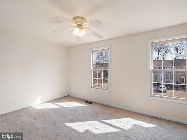 empty room with plenty of natural light, baseboards, a ceiling fan, and carpet floors