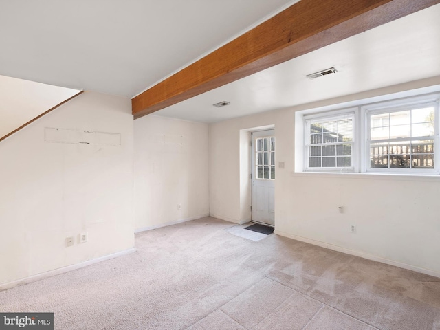 empty room with beam ceiling, baseboards, visible vents, and carpet floors