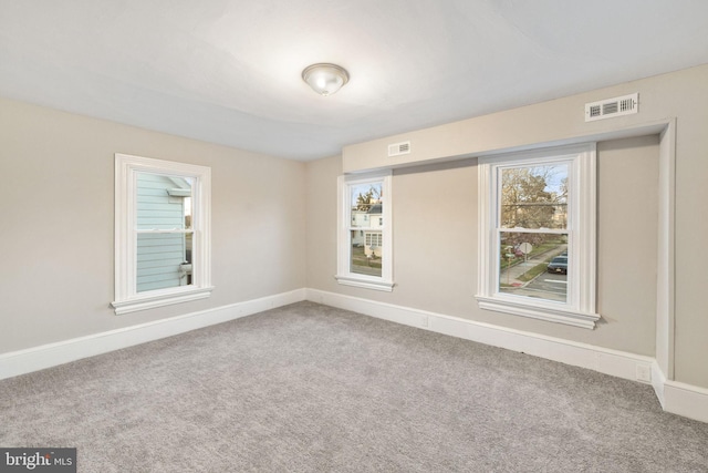 spare room with carpet flooring, visible vents, and baseboards