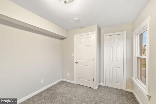 unfurnished bedroom featuring a closet, baseboards, and carpet