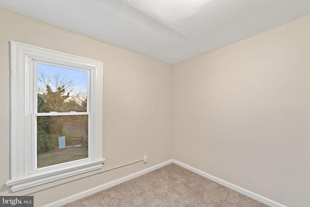 carpeted spare room featuring baseboards