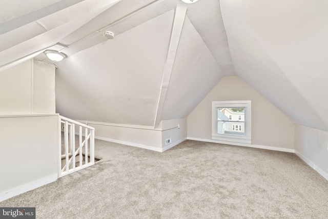 additional living space featuring carpet flooring, baseboards, and vaulted ceiling