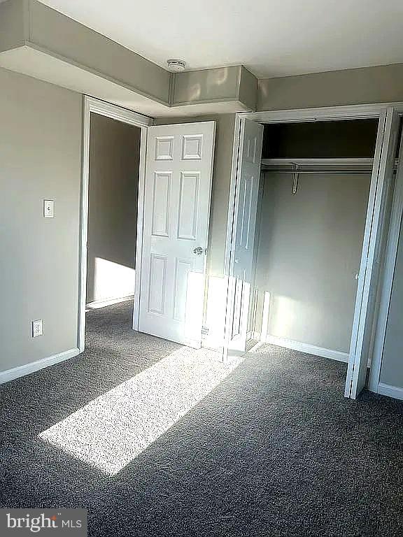 unfurnished bedroom featuring a closet and dark carpet