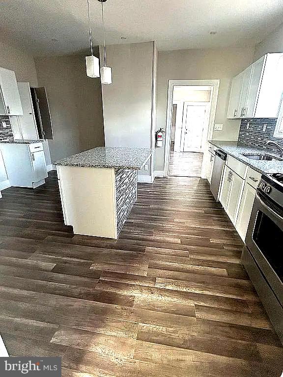 kitchen featuring a center island, white cabinetry, hanging light fixtures, and sink