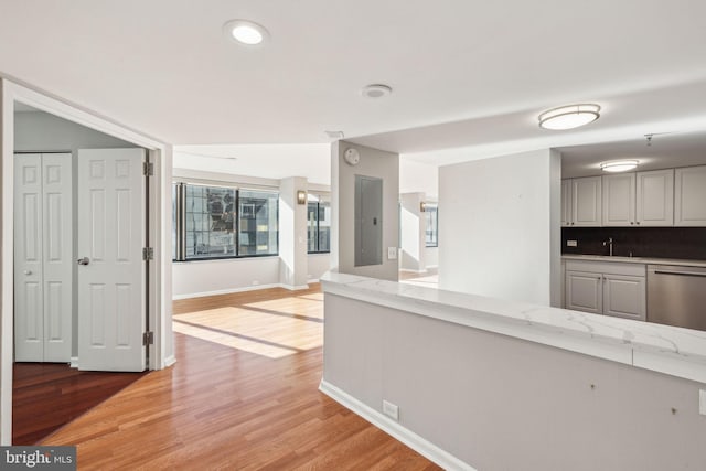 kitchen featuring dishwasher, light hardwood / wood-style floors, light stone counters, and decorative backsplash