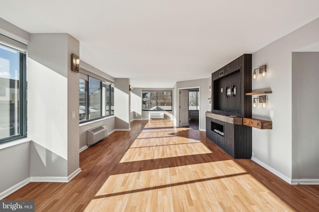 unfurnished living room with radiator, hardwood / wood-style floors, and a wall mounted AC