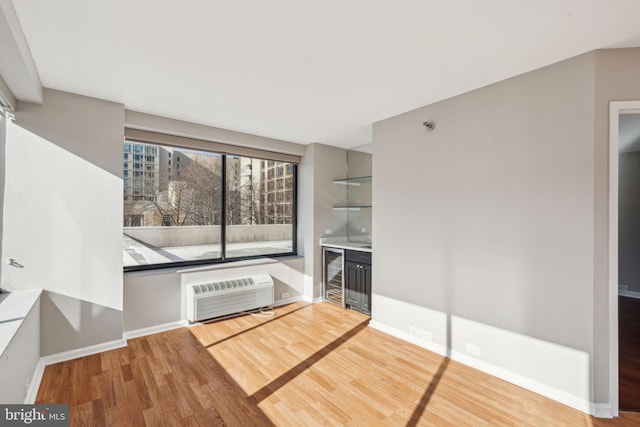 unfurnished living room with a wall unit AC, bar area, beverage cooler, and wood-type flooring