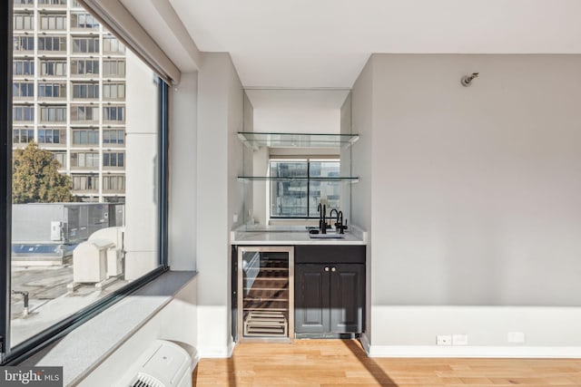 bar featuring wine cooler, sink, and hardwood / wood-style flooring