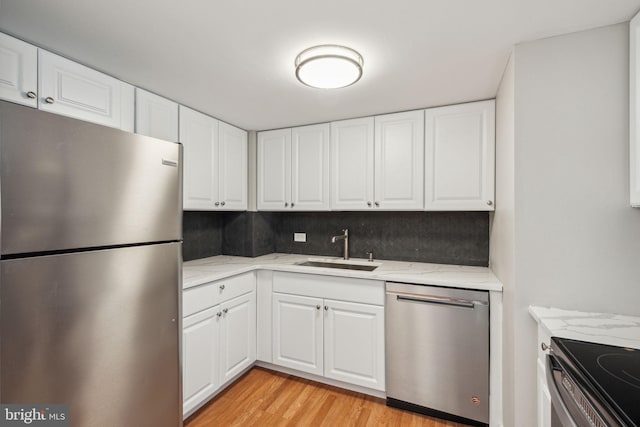 kitchen featuring light stone countertops, white cabinetry, sink, and appliances with stainless steel finishes