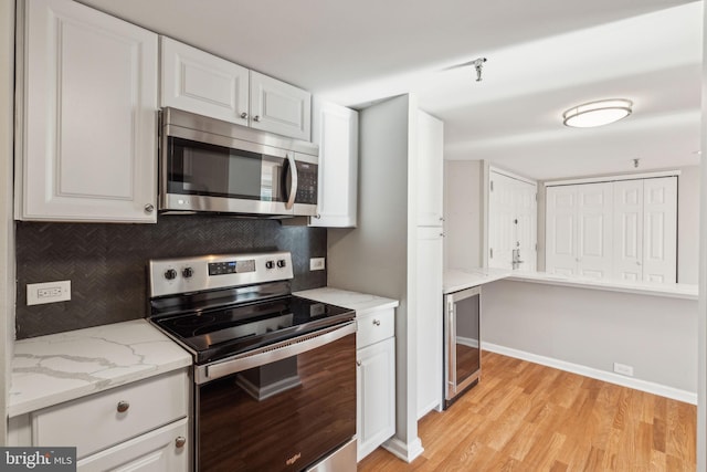 kitchen with decorative backsplash, light stone countertops, stainless steel appliances, light hardwood / wood-style flooring, and white cabinets