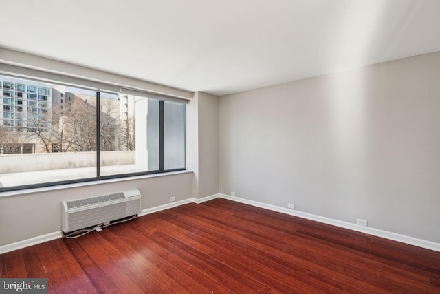 empty room featuring a wall unit AC and wood-type flooring