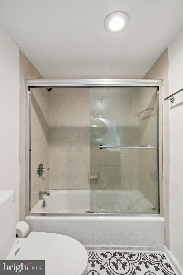 bathroom featuring tile patterned flooring, enclosed tub / shower combo, and toilet