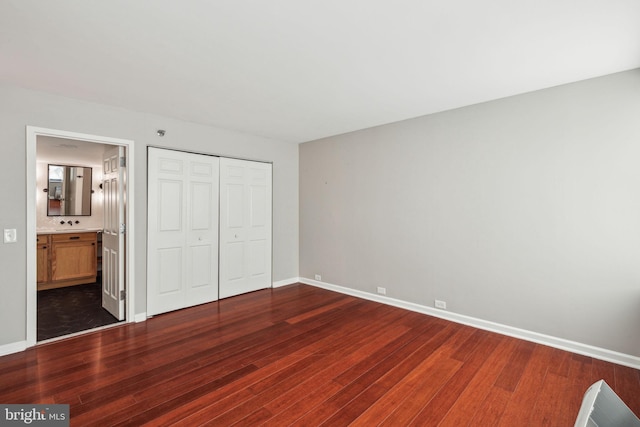 unfurnished bedroom featuring dark hardwood / wood-style flooring, ensuite bathroom, and a closet