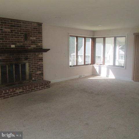 unfurnished living room featuring carpet flooring, a healthy amount of sunlight, and a brick fireplace