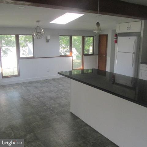 kitchen with decorative light fixtures, white refrigerator, white cabinetry, and a healthy amount of sunlight