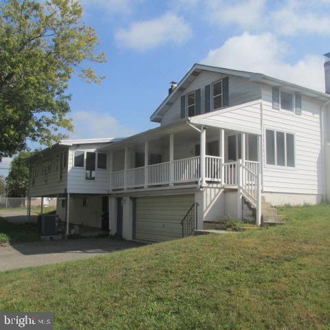 back of house with central air condition unit and a lawn