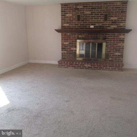 unfurnished living room featuring carpet floors and a brick fireplace