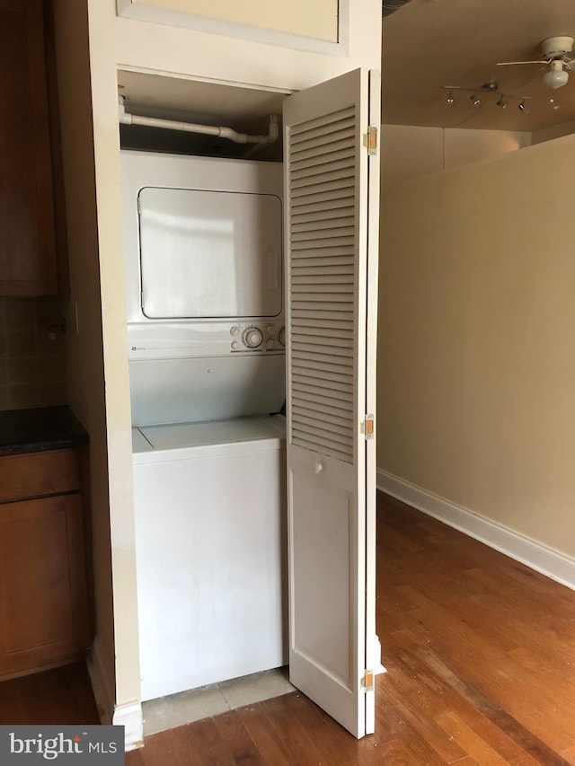 laundry room with ceiling fan, wood-type flooring, and stacked washer and clothes dryer