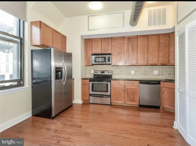 kitchen with decorative backsplash, stainless steel appliances, and light hardwood / wood-style flooring