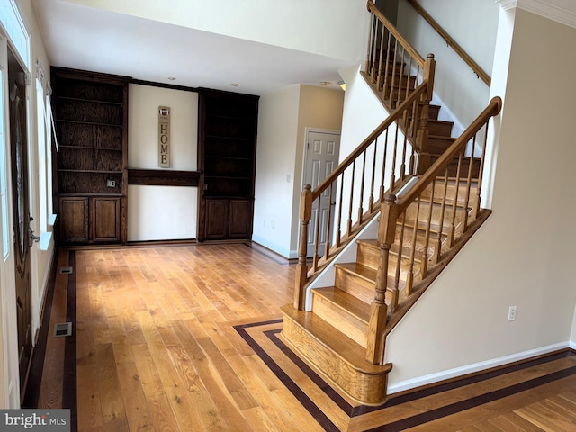 entryway with light wood-type flooring and crown molding