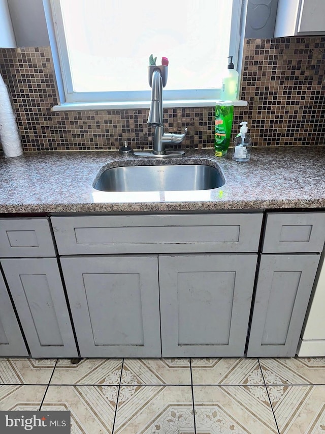 kitchen with tasteful backsplash, gray cabinetry, and sink