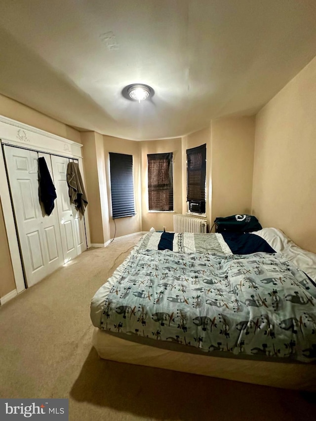 bedroom featuring carpet flooring, radiator heating unit, and a closet