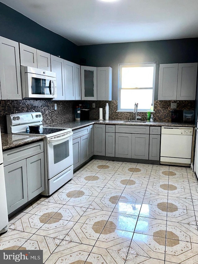 kitchen featuring decorative backsplash, white appliances, gray cabinetry, and sink