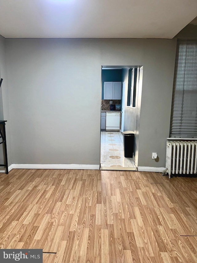 empty room featuring radiator heating unit and light hardwood / wood-style flooring