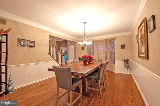 dining area featuring dark hardwood / wood-style floors, crown molding, and a notable chandelier