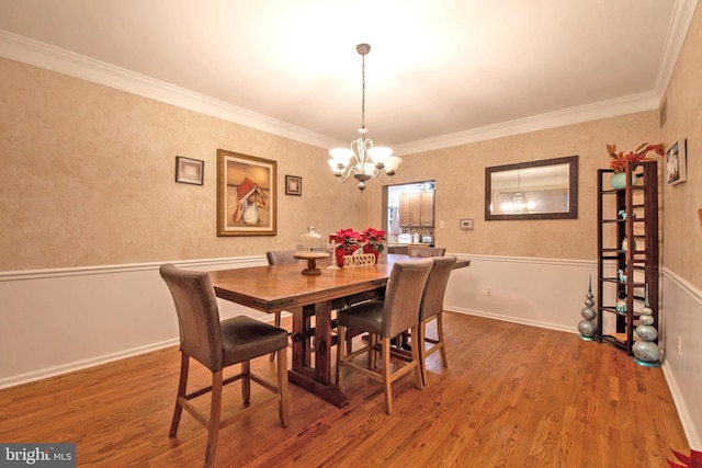 dining space with hardwood / wood-style flooring, an inviting chandelier, and ornamental molding