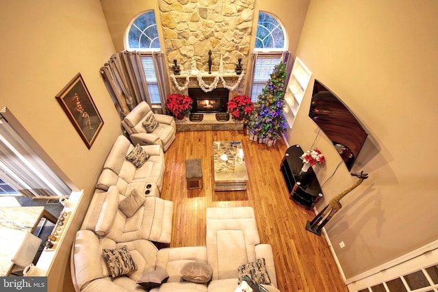 living room featuring hardwood / wood-style flooring, plenty of natural light, a fireplace, and a high ceiling