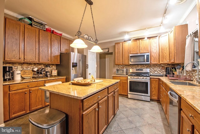 kitchen featuring appliances with stainless steel finishes, rail lighting, sink, decorative light fixtures, and a kitchen island