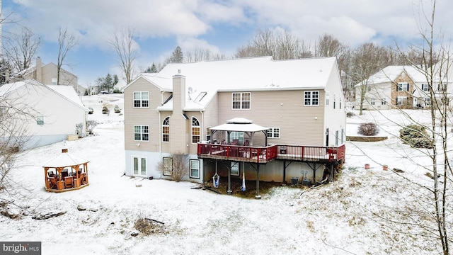 snow covered back of property featuring a wooden deck