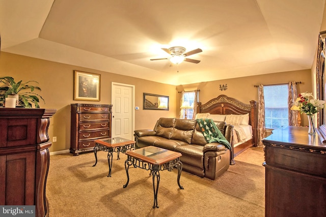 bedroom with a raised ceiling, ceiling fan, and light colored carpet