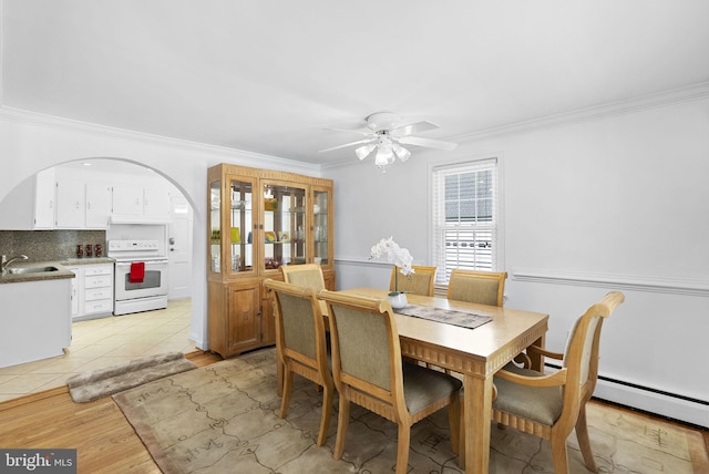 tiled dining space featuring a baseboard radiator, ceiling fan, ornamental molding, and sink