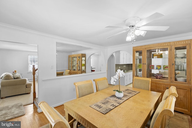 dining room featuring sink, ceiling fan, light wood-type flooring, ornamental molding, and baseboard heating