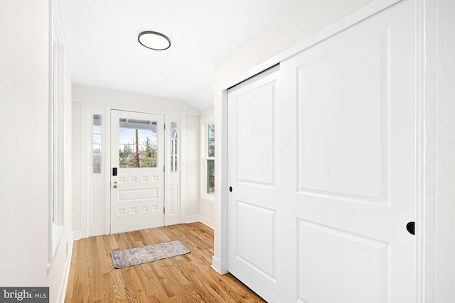 entryway with light wood-type flooring and vaulted ceiling