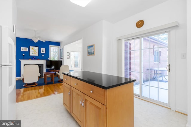 kitchen with ceiling fan, a kitchen island, light wood-type flooring, and white refrigerator